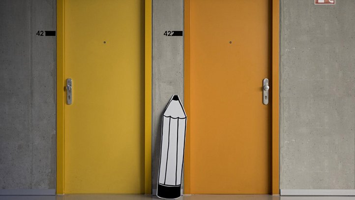 Bleistift aus Pappe zwischen zwei bunten Türen
